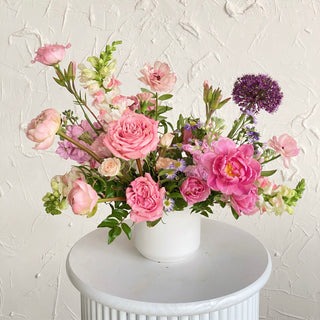 Floral arrangement of pink flowers in a small ceramic vase
