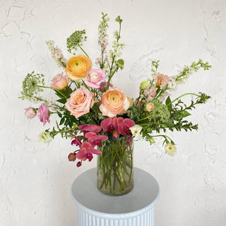 A large floral arrangement with peach, pink, and maroon flowers