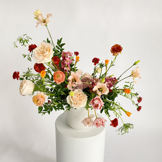 A very large floral arrangement filled with white, pink, orange, and red flowers in a ceramic vase