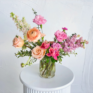 A floral arrangement filled with bright peach and pink flowers
