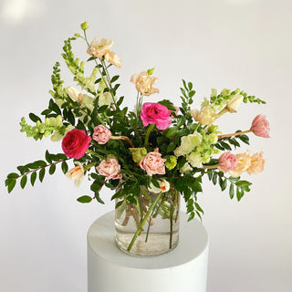 A floral arrangement with bright pink, white, and pastel yellow flowers