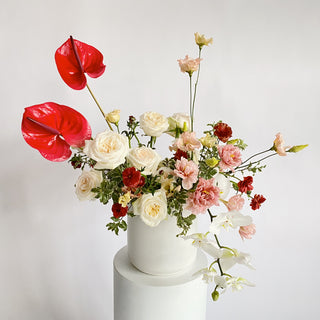 A very large floral arrangement filled with bright red, white, and light pink flowers in a ceramic vase