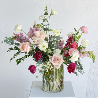 A romantic floral arrangement filled with dusty rose, magenta, and white flowers