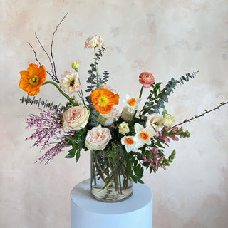 A floral arrangement of orange, white, lavender, and pastel pink flowers