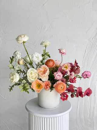 Large floral arrangement of white, peach, pink, and maroon flowers in a ceramic vase