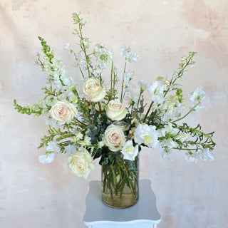 A large, tall floral arrangement filled with white flowers and greenery