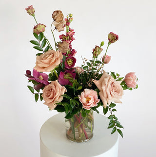 A floral arrangement filled with dusty rose and deep maroon flowers