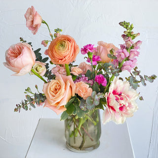 A floral arrangement filled with bright peach and pink flowers