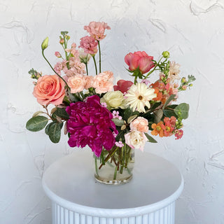 A floral arrangement filled with peach, pink, white, and magenta flowers