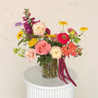A summery floral arrangement filled with pink, red, yellow, and white flowers