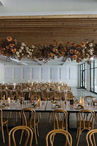 A modern wedding reception space with a hanging floral statement above the head table