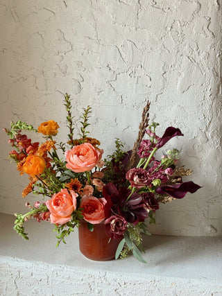 Floral arrangement in a terracotta pot against a textured white wall