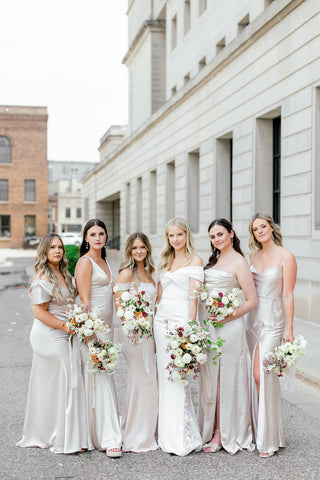 A bride and her five bridesmaids standing together with their bouquets in an outdoor urban downtown setting