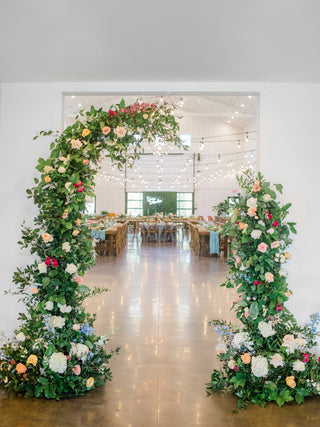 A large floral and greenery asymmetrical arch at The Pines Wedding Venue